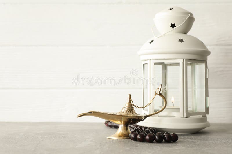 Magischer Aladdin Lamp mit Gebetsperlen und Ramadan-Laterne auf grauer Tabelle lizenzfreie stockbilder Magischer Aladdin Lamp mit Gebetsperlen und Ramadan-Laterne auf grauer Tabelle lizenzfreie stockbilder