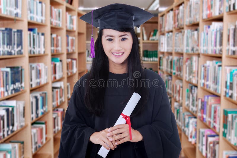 Magistrant/magistrantka mienie dyplom w bibliotece obrazy royalty free Magistrant/magistrantka mienie dyplom w bibliotece obrazy royalty free