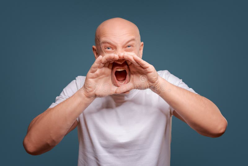 Maglietta bianca d'uso dell'uomo felice bello, tipo che parla fortemente, isolata su fondo blu fotografia stock Maglietta bianca d'uso dell'uomo felice bello, tipo che parla fortemente, isolata su fondo blu fotografia stock