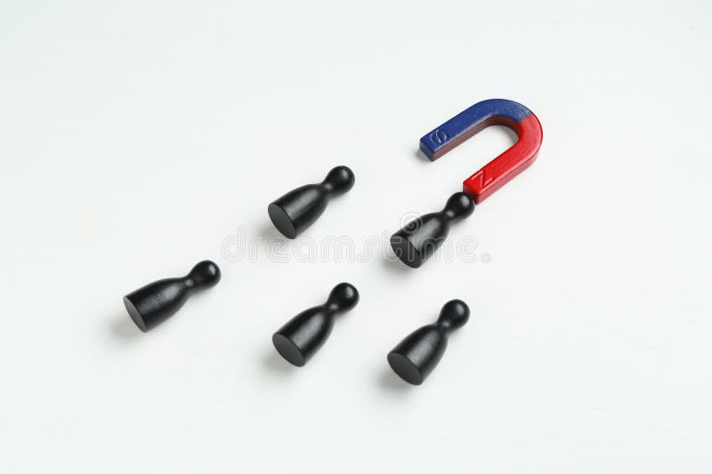 Magnet attracting black game pieces on white stock photography