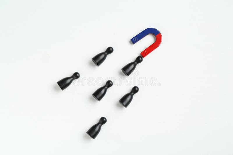 Magnet attracting black game pieces on white background, flat lay royalty free stock photography