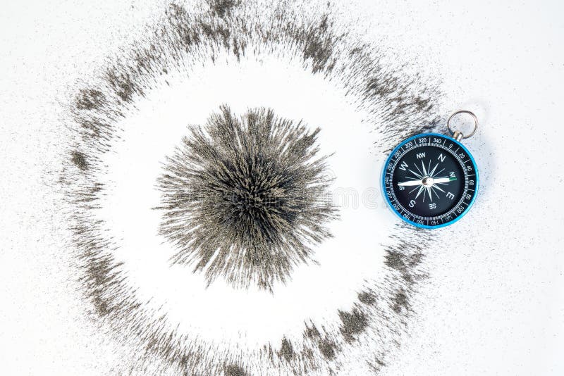 Magnetico radiale a cerchio forte sotto il campo magnetico in polvere di ferro nera con bussola blu su fondo bianco Scientifico immagine stock
