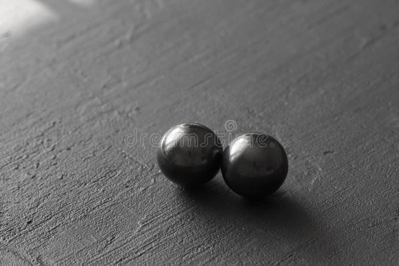 Magnetite di pietra, attrazione, buco nero Le palle naturali di magnetite sono attirate l'un l'altro, su un fondo concreto nero fotografia stock libera da diritti Magnetite di pietra, attrazione, buco nero Le palle naturali di magnetite sono attirate l'un l'altro, su un fondo concreto nero fotografia stock libera da diritti