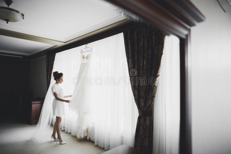 Magnifique mariée en robe posant et se préparant pour la cérémonie de mariage face dans une pièce image libre de droits