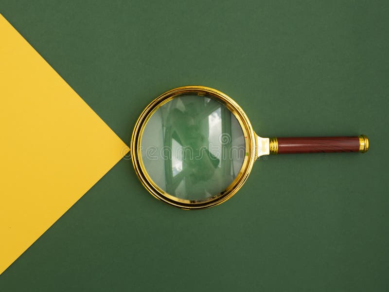 Magnifying glass over green background with yellow paper beam as symbol of insight, discovery and finding answers and stock photo