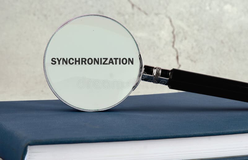A magnifying glass is placed on an open book, highlighting the word synchronization. The setting features a simple stock photography