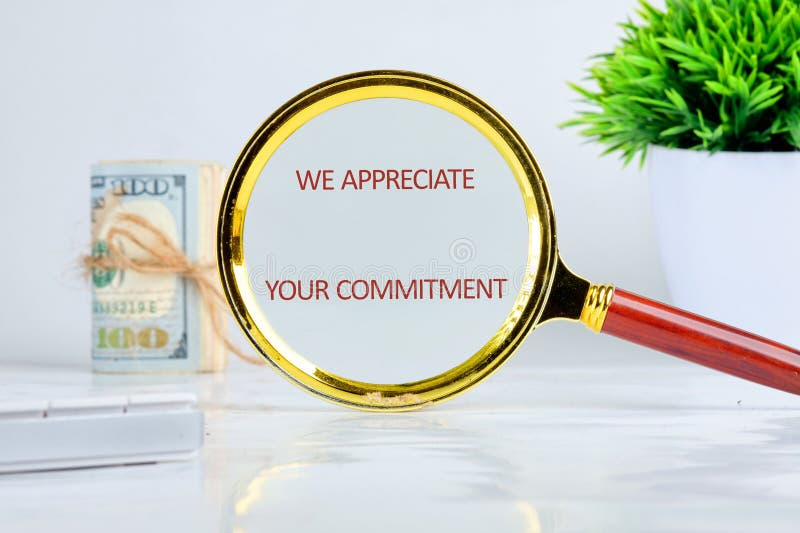 Magnifying Glass Revealing a Message of Appreciation for Commitment Against a Backdrop of Currency and a Plant royalty free stock photo