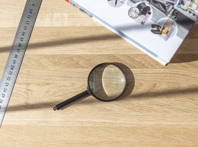 Magnifying glass, technical book and ruler on wooden desk. Concept of study and research, finding answers and solutions royalty free stock images