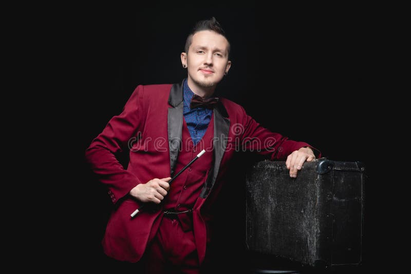 Mago con bacchetta magica e valigia su fondo nero fotografia stock