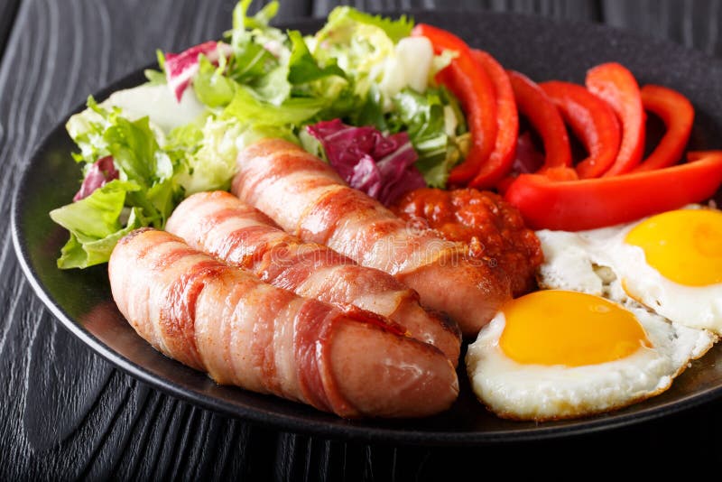 Maiali della prima colazione in salsiccie fritte coperte avvolte in bacon, uova fotografia stock libera da diritti Maiali della prima colazione in salsiccie fritte coperte avvolte in bacon, uova fotografia stock libera da diritti