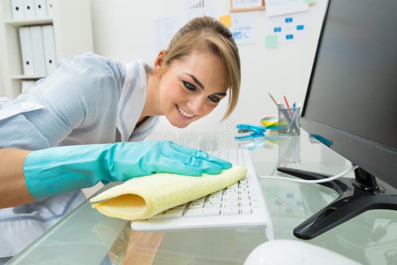 Maid cleaning keyboard at desk royalty free stock photos
