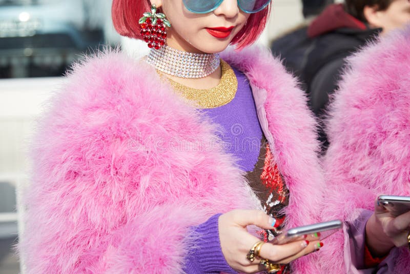 Mailand am 21. Februar : Frau mit rosa Pelzmantel und -haar, die Smartphone vor Gucci-Modeschaumailand-Modewochenstraße betrachtet