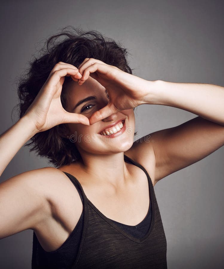 Main dans le coeur heureux et portrait de femme en studio avec geste main pour succès soutien et soins. joie de sourire et photographie stock