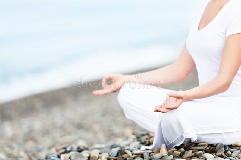 Main de femme méditant dans une pose de yoga sur la plage