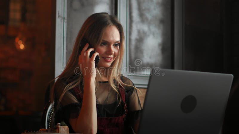 Main de femme tenant le téléphone portable blanc sur une table avec un ordinateur portable dans le bureau