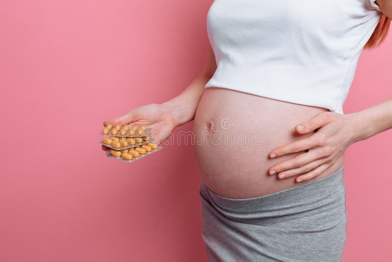 Main de jeunes habillages transparents de participation de femme enceinte de pilules Réception des vitamines pendant la grossesse photo stock Main de jeunes habillages transparents de participation de femme enceinte de pilules Réception des vitamines pendant la grossesse photo stock