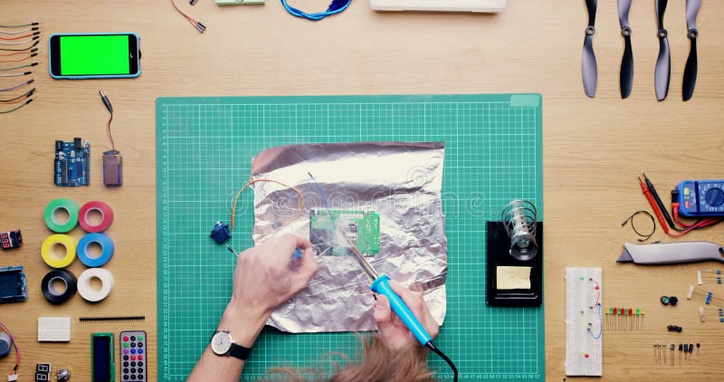 Main de personne et technicien soudage circuit composant ou téléphone vert écran ci-dessus pour tutoriel ou classe en ligne banque de vidéos