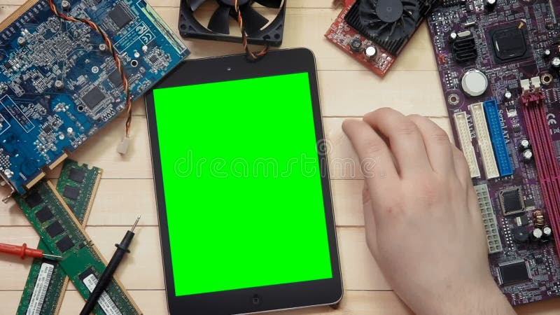 Main de technicien d'ordinateur de vue supérieure et comprimé numérique avec l'écran vert au bureau en bois avec des outils et él clips vidéos