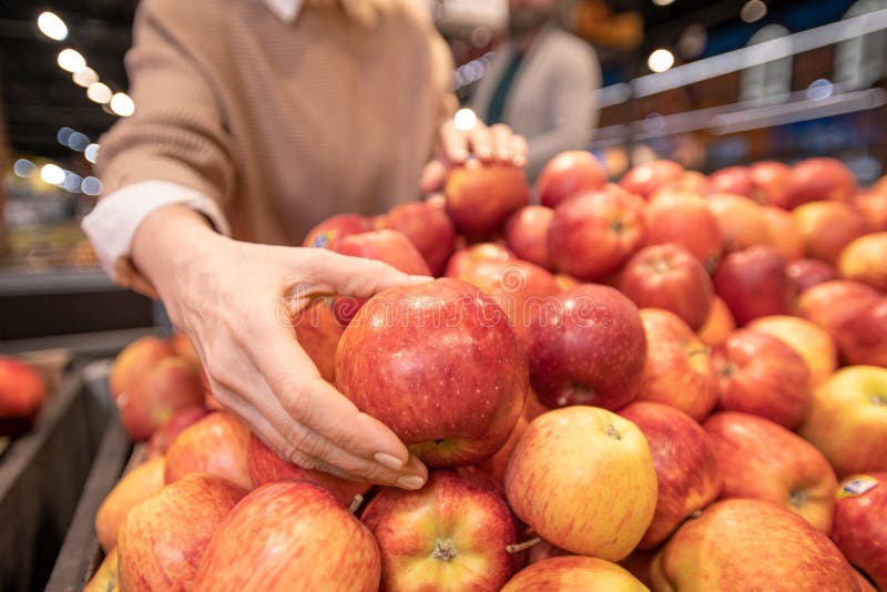 Main du adolescente mûr au choix des pommes rouges fraîches sur l'affichage de fruits