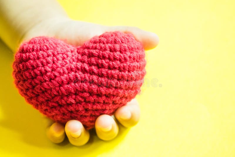 Main du ` s d'enfant avec un coeur rouge sur le fond jaune photographie stock libre de droits Main du ` s d'enfant avec un coeur rouge sur le fond jaune photographie stock libre de droits