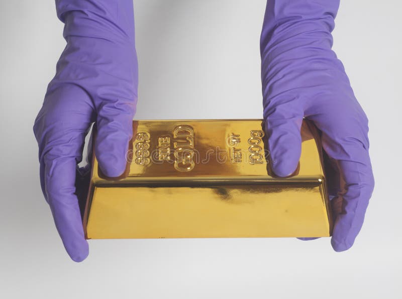 Main du ` s de femme dans les gants pourpres tenant un lingot d'or photographie stock libre de droits Main du ` s de femme dans les gants pourpres tenant un lingot d'or photographie stock libre de droits