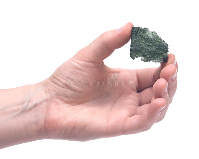 Woman`s hand holding Moldavite form of tektite found along the banks of the river Moldau in Czech republic isolated on white background. Woman`s hand holding Moldavite form of tektite found along the banks of the river Moldau in Czech republic isolated on white background