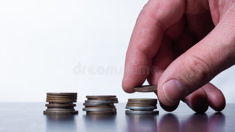Main empilant de petites pièces de monnaie sur une table photographie stock Main empilant de petites pièces de monnaie sur une table photographie stock
