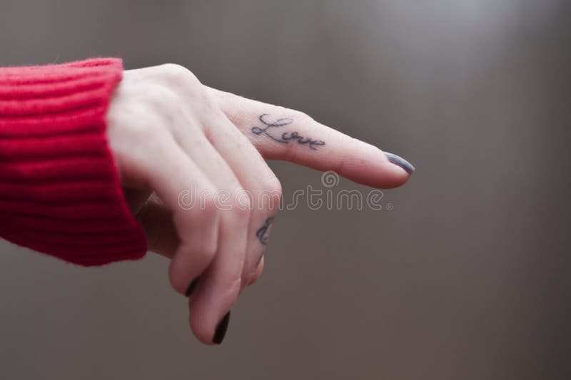 Main femelle d'isolement avec un tatouage d'AMOUR sur son doigt image libre de droits Main femelle d'isolement avec un tatouage d'AMOUR sur son doigt image libre de droits