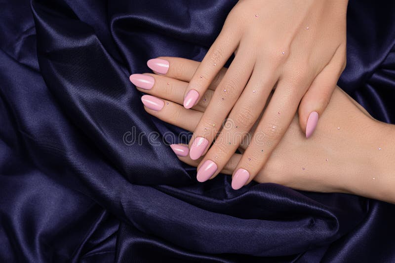 Main féminine avec la conception de l'ongle rose Manucure de vernis à ongles scintillante de Rose Main de femme sur le fond pourp