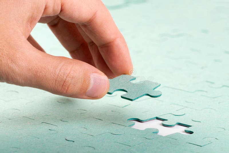 Main insérant la partie manquante du puzzle denteux photos libres de droits Main insérant la partie manquante du puzzle denteux photos libres de droits