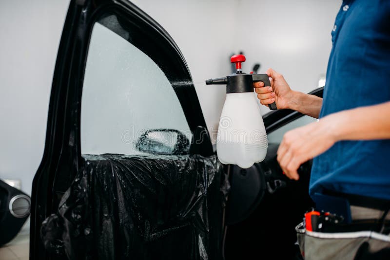 Male hand with spray, car window tint installation process, installing procedure, tinting film. Male hand with spray, car window tint installation process, installing procedure, tinting film