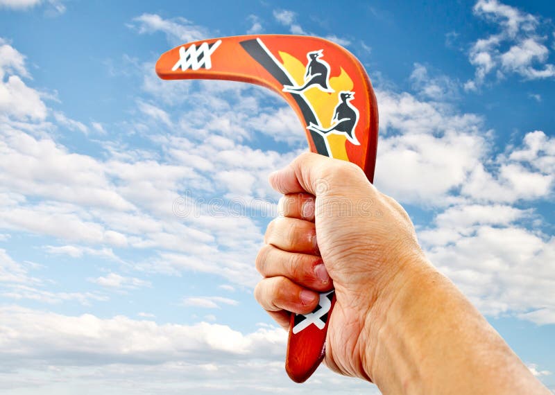 Hand holding a boomerang pointing to blue sky. Hand holding a boomerang pointing to blue sky