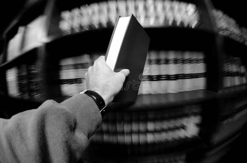 Hand holding book in an old library in background. Hand holding book in an old library in background