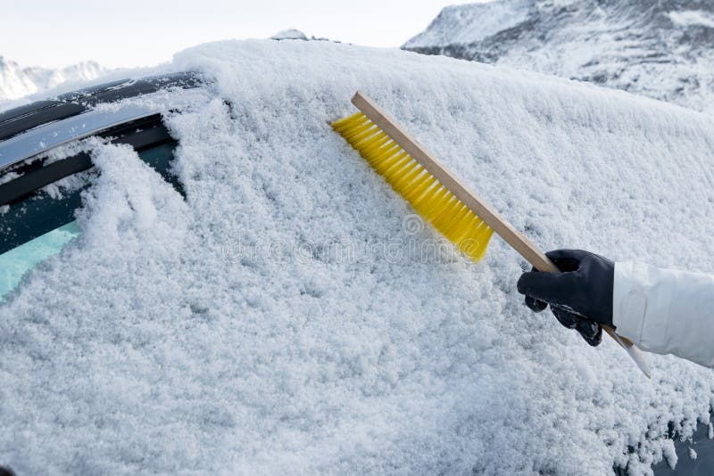 Main utilisant la neige rapide de brosse sur le pare-brise de voiture photographie stock libre de droits Main utilisant la neige rapide de brosse sur le pare-brise de voiture photographie stock libre de droits