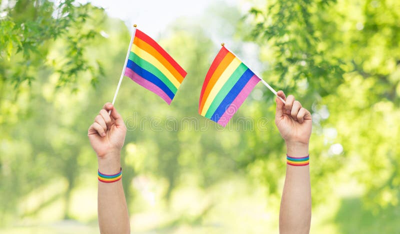 Mains avec des drapeaux et des bracelets d'arc-en-ciel de fierté gaie photo stock Mains avec des drapeaux et des bracelets d'arc-en-ciel de fierté gaie photo stock
