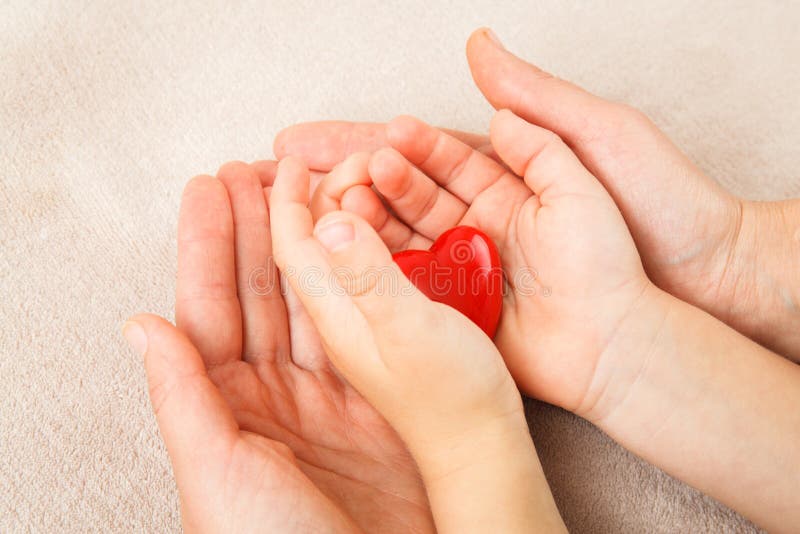 Mains d'adulte et d'enfant tenant le coeur rouge photos libres de droits Mains d'adulte et d'enfant tenant le coeur rouge photos libres de droits