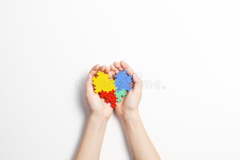 Mains d'enfant tenant le coeur coloré sur le fond blanc Concept de jour de conscience d'autisme du monde photos stock Mains d'enfant tenant le coeur coloré sur le fond blanc Concept de jour de conscience d'autisme du monde photos stock