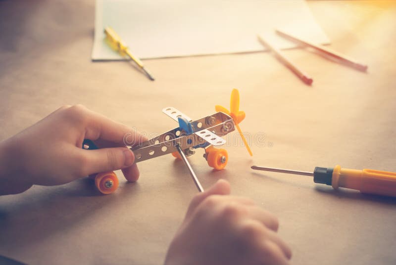 Mains d'enfants avec l'avion de fer de jouet Constructeur en métal avec des tournevis Le rêve, jouent et créent images libres de droits Mains d'enfants avec l'avion de fer de jouet Constructeur en métal avec des tournevis Le rêve, jouent et créent images libres de droits