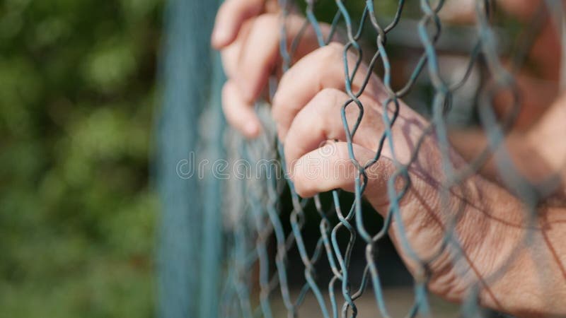 Mains d'homme accrochant dans une barrière métallique en prison photos libres de droits Mains d'homme accrochant dans une barrière métallique en prison photos libres de droits