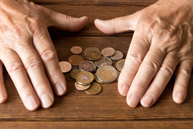 Mains d'un homme plus âgé avec de diverses pièces de monnaie sur une table en bois Th images libres de droits Mains d'un homme plus âgé avec de diverses pièces de monnaie sur une table en bois Th images libres de droits