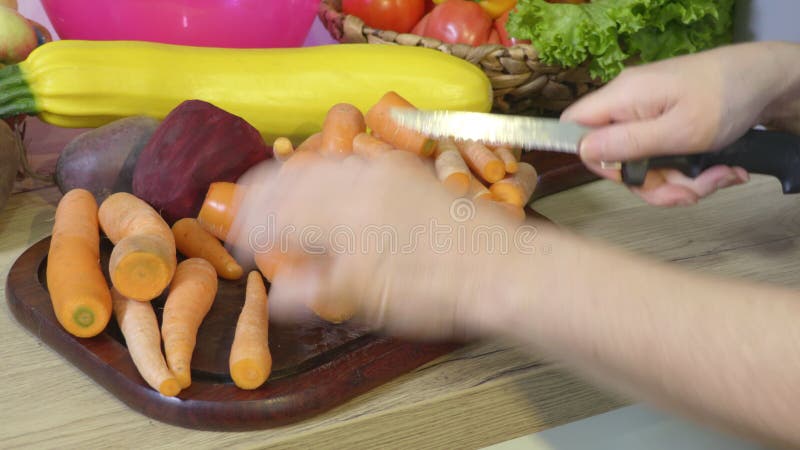Mains de femme coupant des légumes dans la cuisine