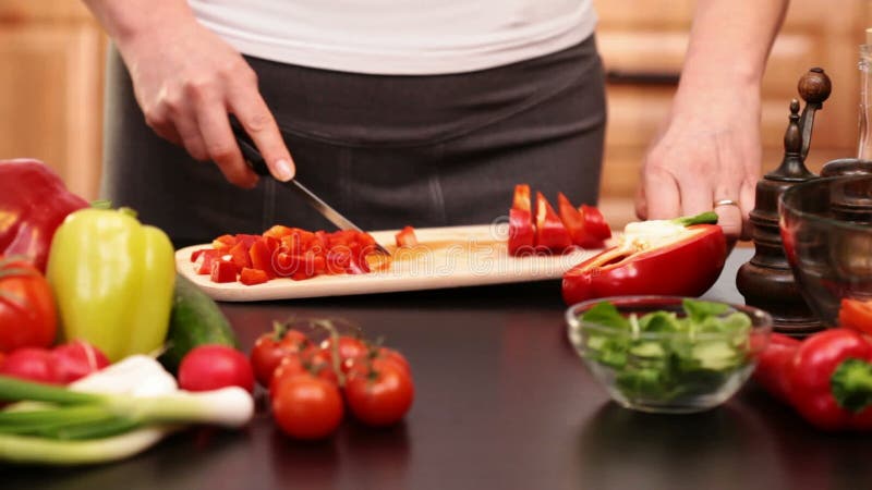 Mains de femme coupant les tranches rouges de paprika banque de vidéos
