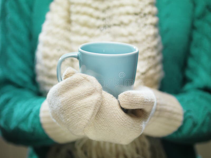 Mains de femme dans des mitaines de laine blanches tenant une tasse confortable avec du cacao, le thé ou le café chaud Concept de image libre de droits Mains de femme dans des mitaines de laine blanches tenant une tasse confortable avec du cacao, le thé ou le café chaud Concept de image libre de droits
