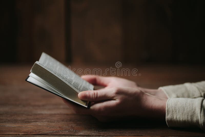 Mains de femme sur la bible elle lit et prie images stock
