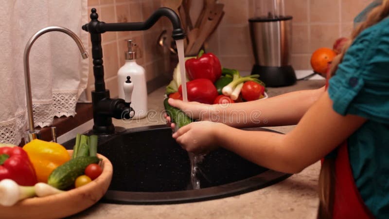 Mains de jeune fille lavant un concombre banque de vidéos