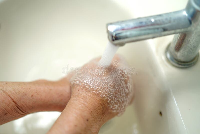 Mains de lavage de patiente d'une cinquantaine d'années asiatique de femme dans la salle d'hôpital : concept médical sain images stock Mains de lavage de patiente d'une cinquantaine d'années asiatique de femme dans la salle d'hôpital : concept médical sain images stock