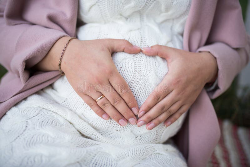 Mains de Mother’s dans une forme de coeur tenant un ventre Fermez-vous vers le haut du ventre du ` s de femme enceinte Prenancy photos stock Mains de Mother’s dans une forme de coeur tenant un ventre Fermez-vous vers le haut du ventre du ` s de femme enceinte Prenancy photos stock