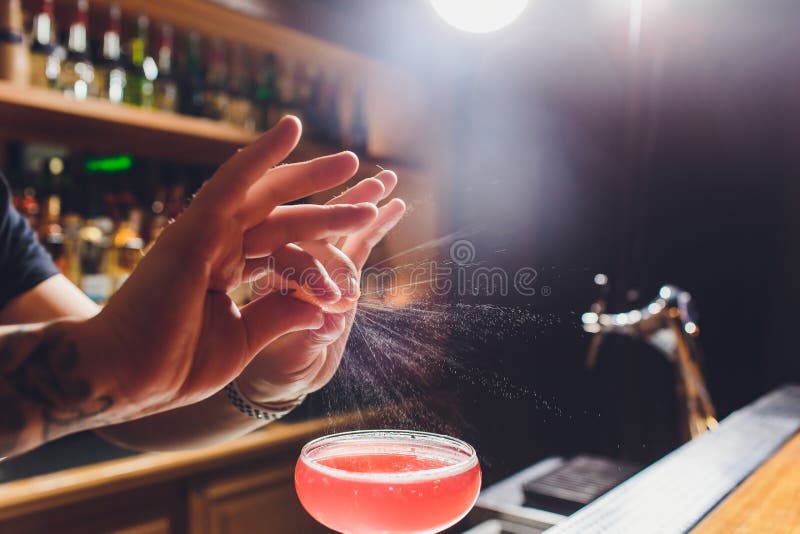 Mains du barman s arrosant le jus dans le verre de cocktail rempli de boisson alcoolis?e sur le fond fonc? photos libres de droits Mains du barman s arrosant le jus dans le verre de cocktail rempli de boisson alcoolis?e sur le fond fonc? photos libres de droits