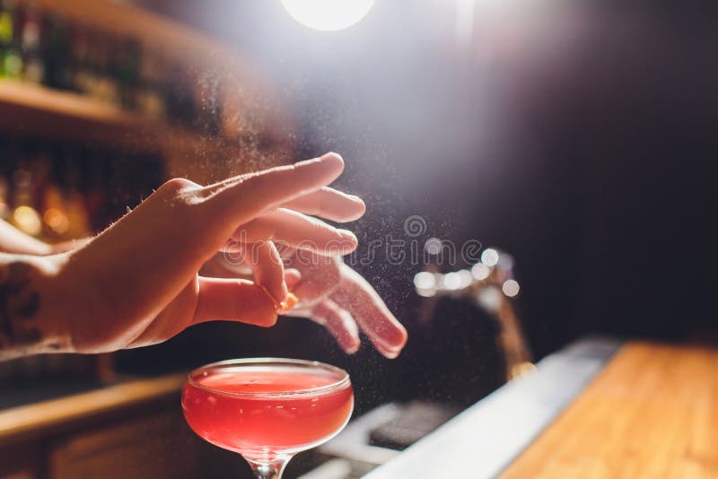 Mains du barman s arrosant le jus dans le verre de cocktail rempli de boisson alcoolis?e sur le fond fonc? image stock Mains du barman s arrosant le jus dans le verre de cocktail rempli de boisson alcoolis?e sur le fond fonc? image stock