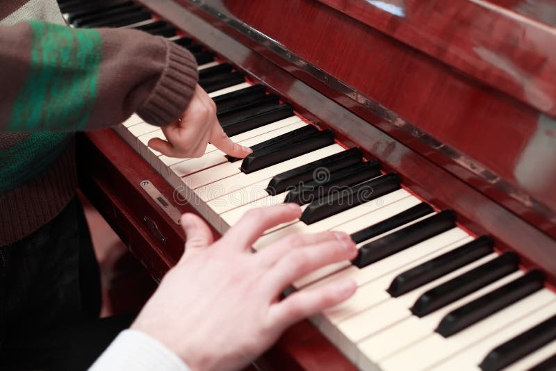 Mains du père et du fils jouant sur le piano brun images stock Mains du père et du fils jouant sur le piano brun images stock